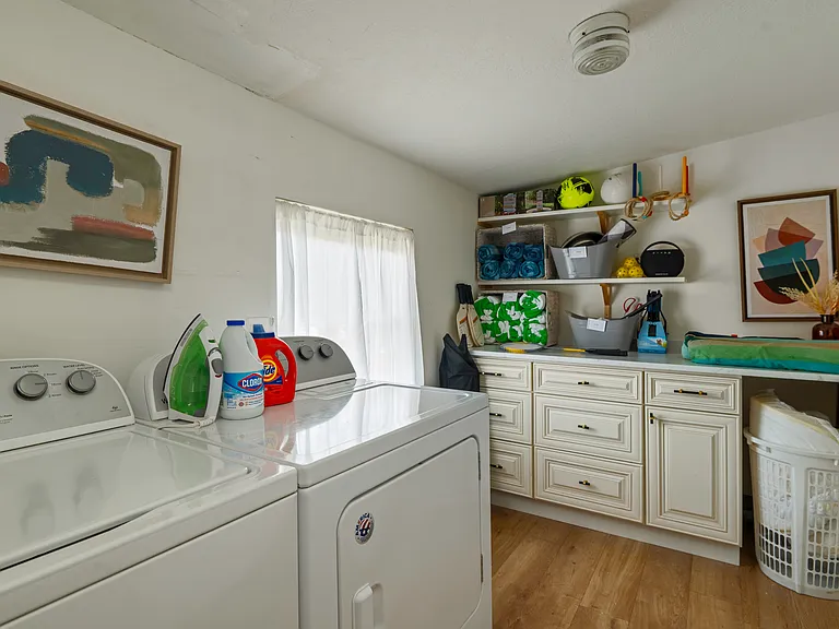 laundry room with washer & dryer, Iron and Ironing board, and storage for yard games, fire pit starters, and bbq tools