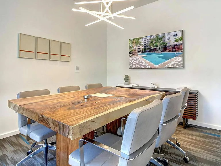 Community Workspace with Wood Table, TV, and Modern Light Fixture