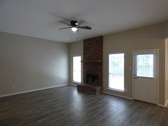 Living room showing fireplace, two windows and back door. Perspective is from hallway leading to bedrooms and guest bath. Dining room is to right of picture.