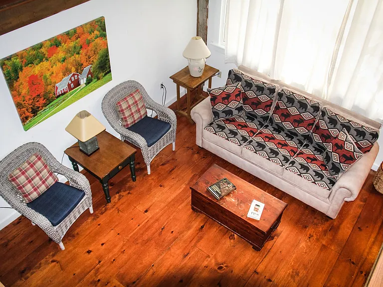 Open living room (wood stove not shown here) has large windows and ceiling fan, as viewed from loft.