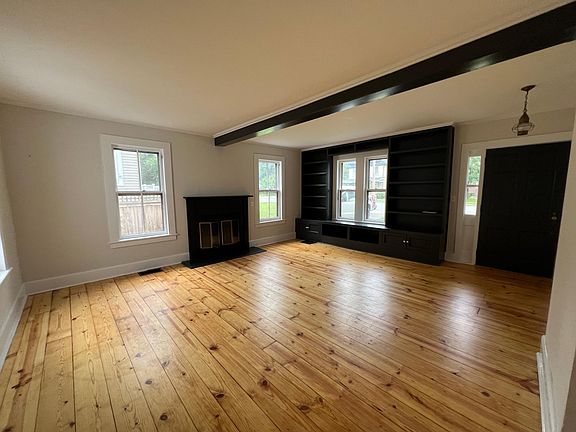 Living room with wood burning fireplace and built in shelving.