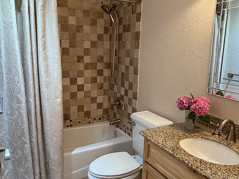 Guest bathroom with custom granite shower and counter. Travertine tile throughout. Even a designer toilet!