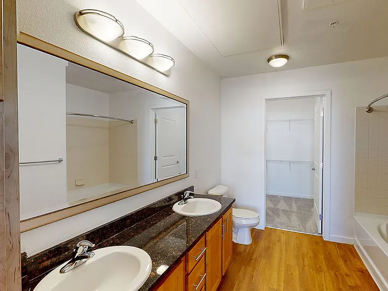 Apartment bathroom with wood-style flooring and double sinks.