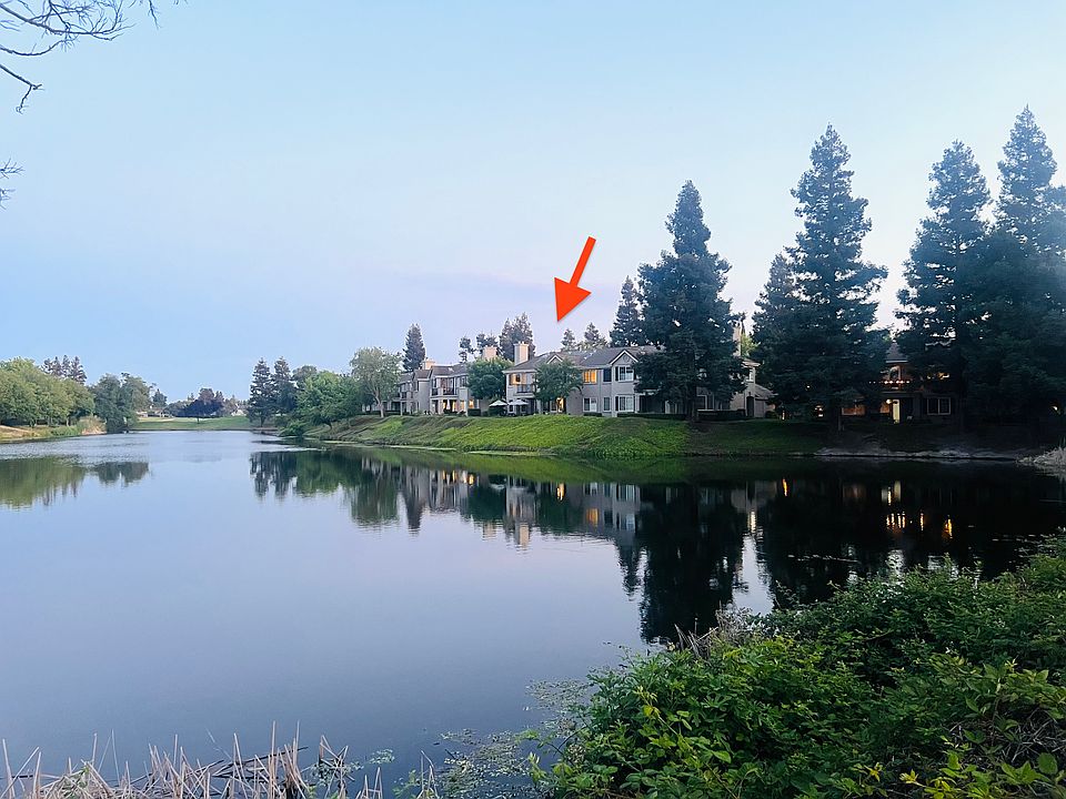 View of the listing from across Teal Lake. Gaze upon your future home from across the serene waters of Teal Lake! This stunning condo, marked by the arrow, offers an idyllic retreat within the exclusive Brookside community.