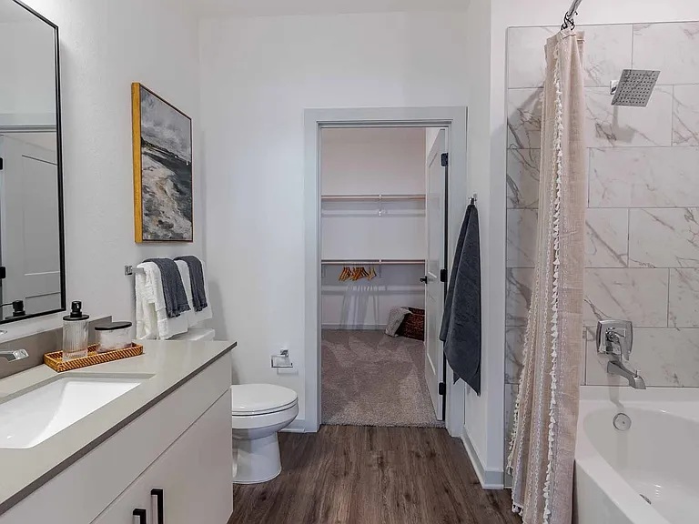 Spa-inspired bathroom with a soaking tub, marble-style tile, and connected walk-in closet. Spa-inspired bathroom with a soaking tub, marble-style tile, and connected walk-in closet.
