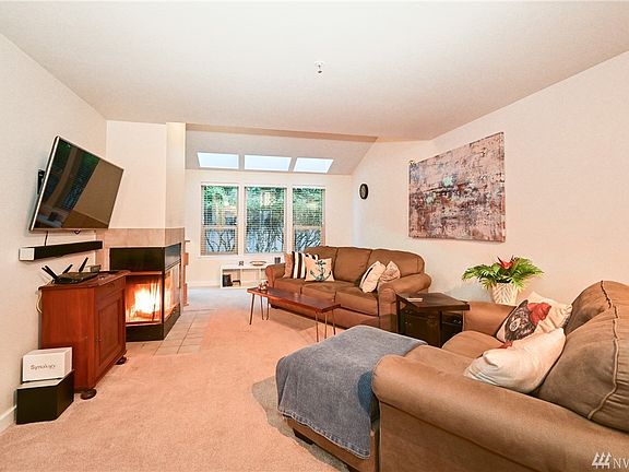 Living room with brand new carpet, large windows for natural lighting, door to the back patio, and a beautiful wood fireplace for those cold NW nights.