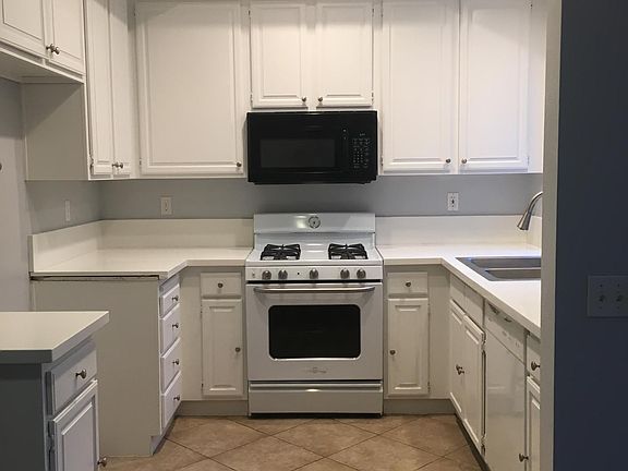 Kitchen with raised can lighting and crown molding. New quartz countertops, painted cabnets, new sink / faucet, newer stove - microwave and dishwasher.