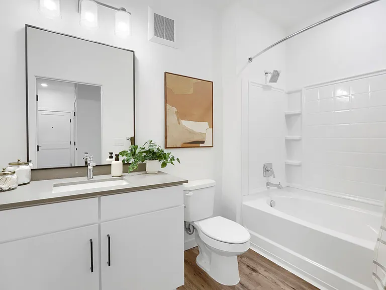 Clean, bright, and thoughtfully finished. The B2 secondary bathroom features a white vanity with quartz countertop, black-framed mirror, and a full tub-shower combo.
