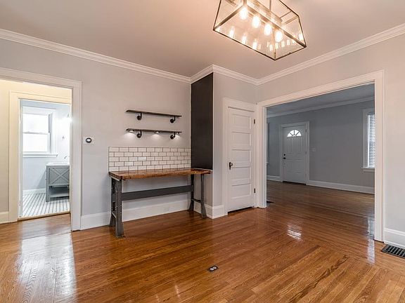 Dining room features a built in prep or serving area with shelves, chandelier, hardwood floors, and a closet