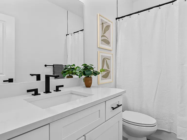 Well-appointed bathroom with a large vanity, matte-black fixtures, and a full tub/shower with curtain for easy upkeep.
