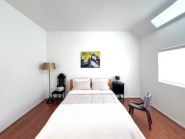 Minimalist master bedroom suite featuring high ceilings, a modern layout, and an architectural skylight that floods the room with natural light.