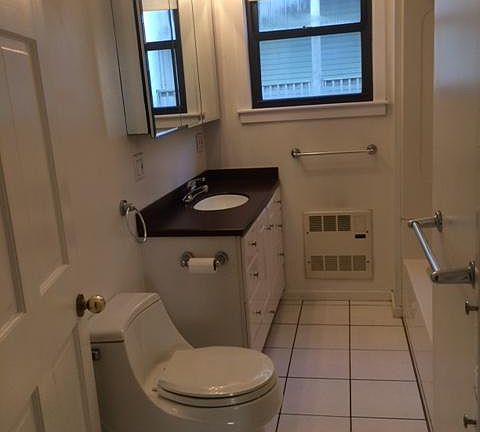 Bathroom with well kept vanity, full tub and laundry shoot