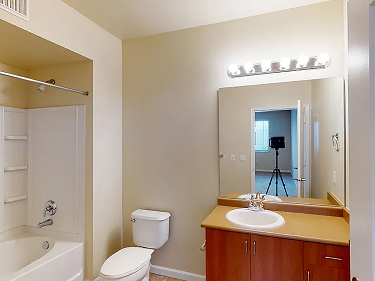 Apartment bathroom with large soaking tub and wood-style flooring.