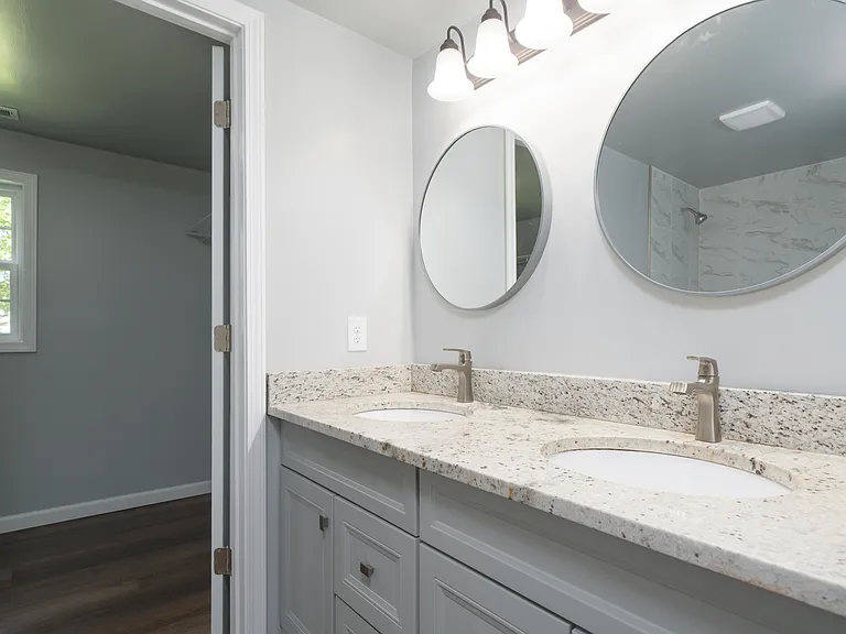 Primary full bath with double sinks, new vanity with granite top, tub/shower combo with tile surround, and adjoining walk-in closet.
