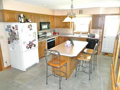 Kitchen with microwave, dishwasher, gas range, and island, including bar stool