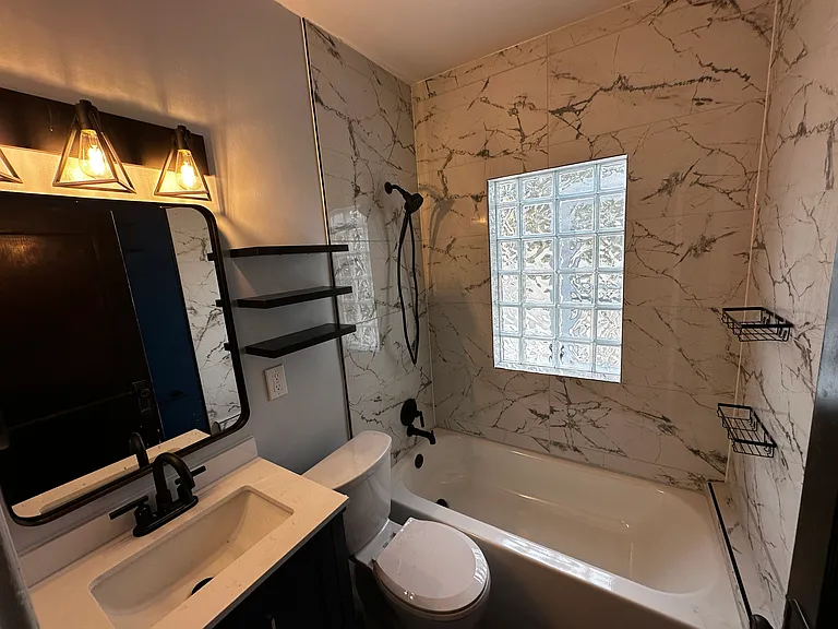 The elegant bathroom. Glass block natural light, new tub with marble surround.