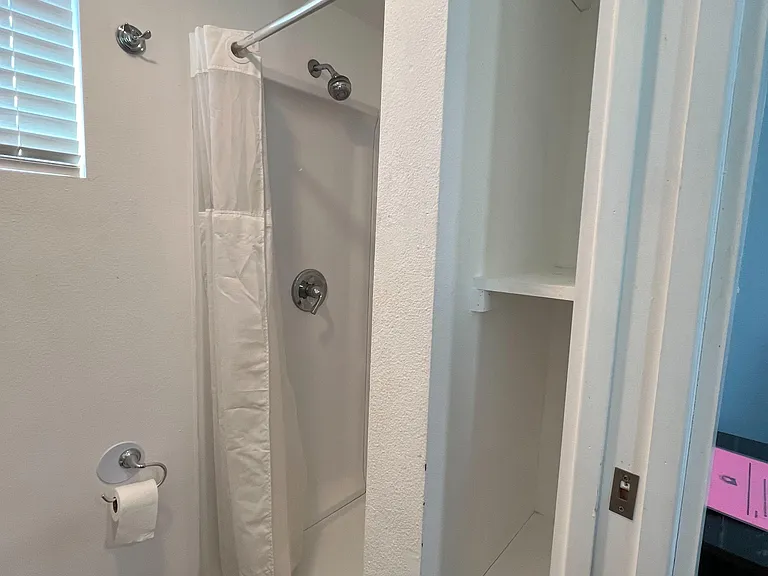 Bathroom features a tub/shower combo with updated fixtures, a window for ventilation, and built-in shelving for linens.