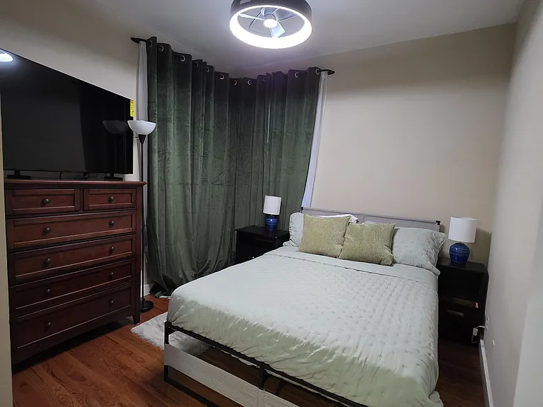 cozy 2nd bedroom with large dresser and 55" smart TV. Bedroom equipped with black out curtains; firm mattress