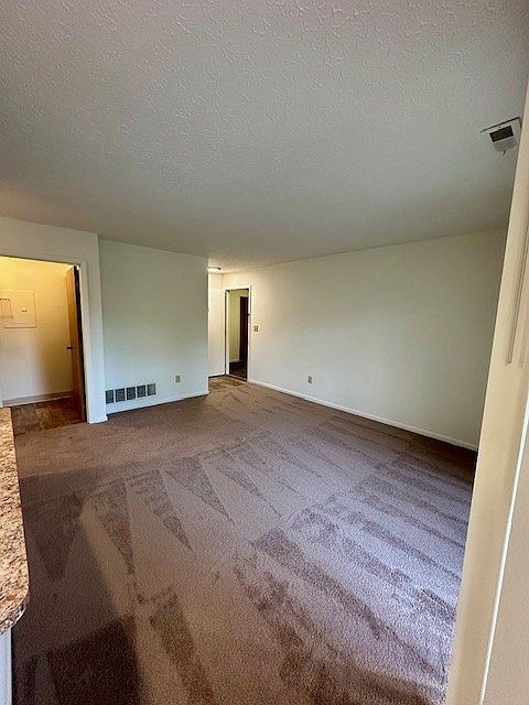 View of the living room and front door of the unit from the bar area of the kitchen