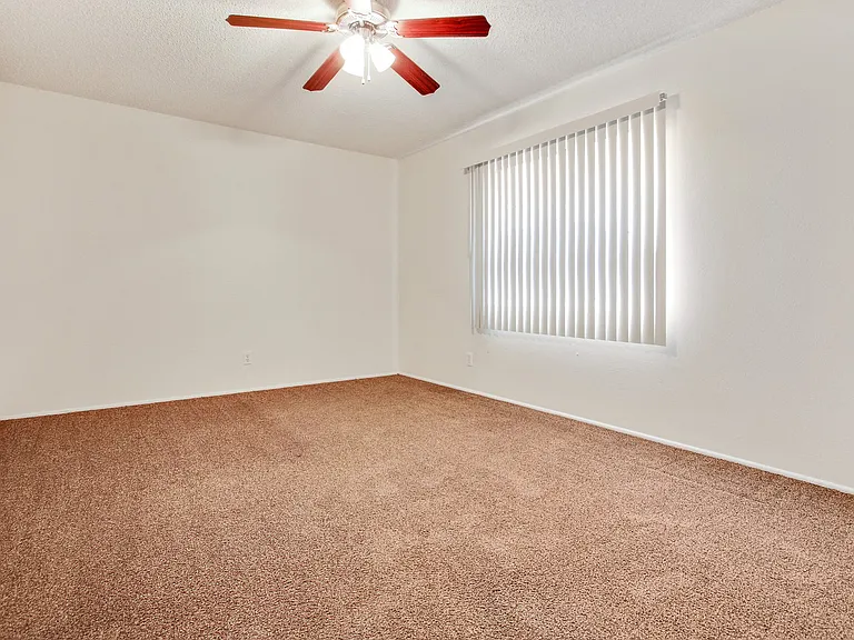 Bedroom with ceiling fan and carpeted floors, vertical window blinds on the right