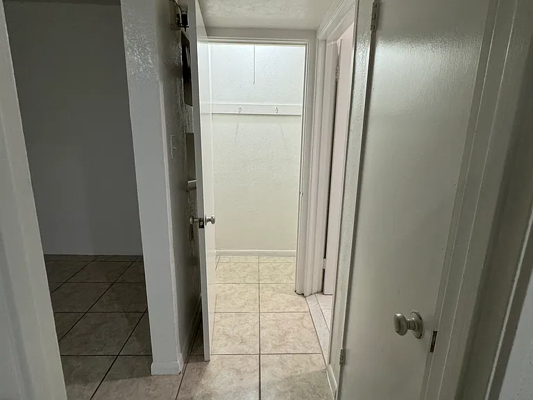 Hallway from the bedroom leading to the closets, bathroom, and living room