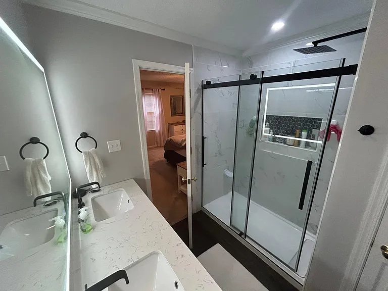 Remodeled primary en-suite bathroom featuring modern lighted mirror, walk-in shower, and double vanity.