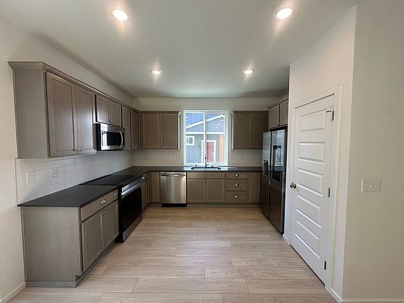 Large open kitchen with Samsung appliances, soft close drawers, solid surface countertops, large sink overlooking the front yard