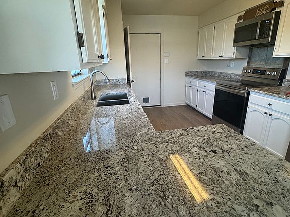 Updated kitchen featuring brand-new granite countertops, Samsung refrigerator, dishwasher, and stove. Complemented by ample cabinet space for all your kitchen essentials and pantry with shelving.
