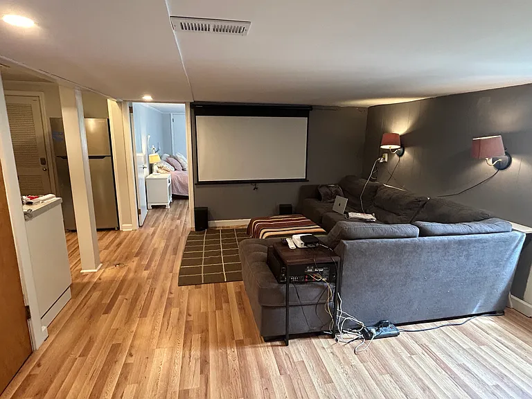 lower level living area - low ceilings perfect for TV area. Lower level offered partially furnished if desired: sectional, queen bed, piano, rocking chair, basic kitchen items, basic flat screen TV.