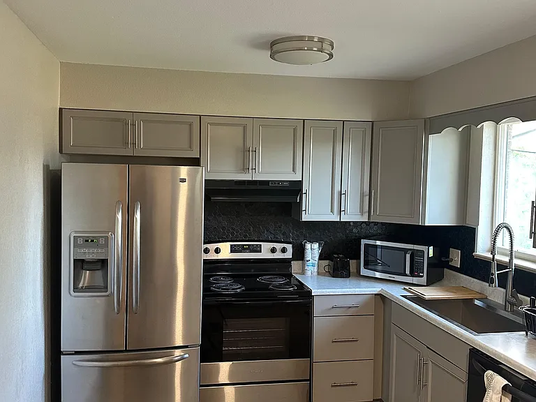 Efficient kitchen with ample gray cabinetry, stainless-steel appliances, and a windowed sink for everyday convenience.