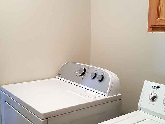 Laundry area with washer, dryer, clothing rod, and cabinet.