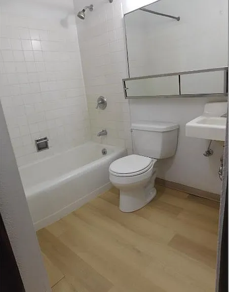 Bathroom has a very large well-lit mirror above toilet and sink.