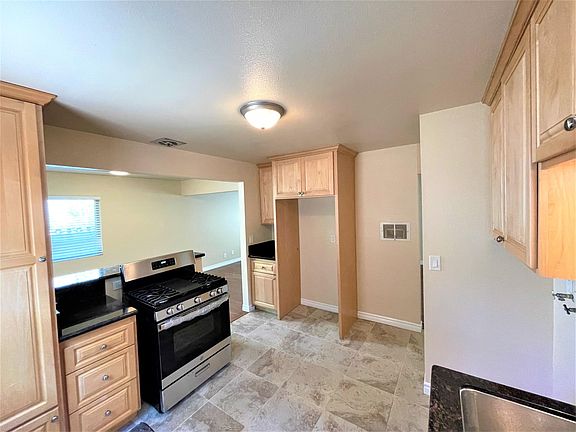 Kitchen with tile flooring, maple cabinets, granite counters and new stainless range.