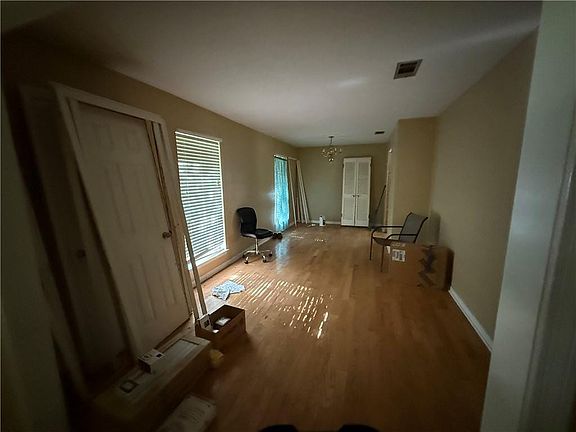 Empty room featuring an inviting chandelier, light wood-type flooring, visible vents, and baseboards