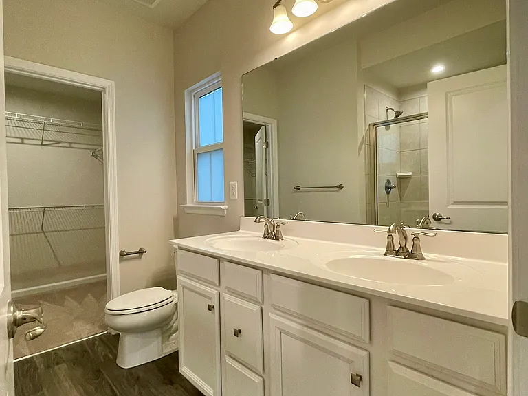 Primary bathroom with dual vanities and large walk-in closet