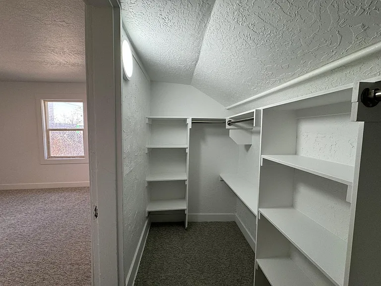 Spacious walk-in closet off the primary bedroom with built-in shelving and plenty of storage.