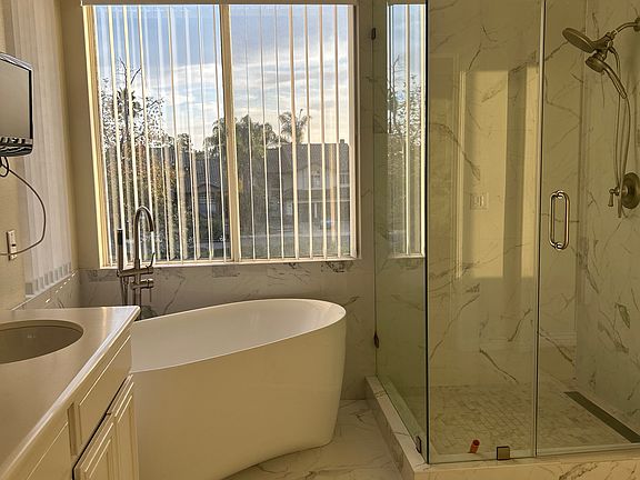 Upscale luxury master bath with free standing soaking tub and separate shower with marble walls and flooring