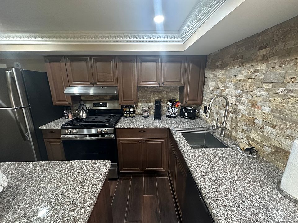 The kitchen area includes a coffee bar, stainless steel appliances, and an island with two stools.