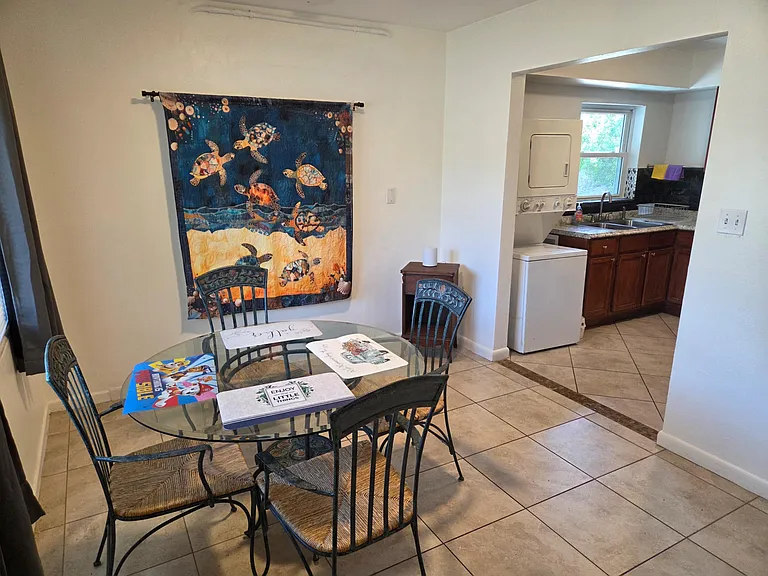 Dining area with a round glass-top table, seating for four, and convenient access to the adjoining kitchen and laundry.