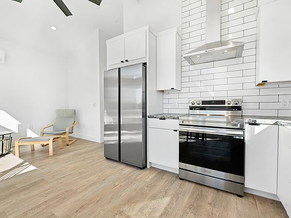 Kitchen area with French door refrigerator, stove and hood.
