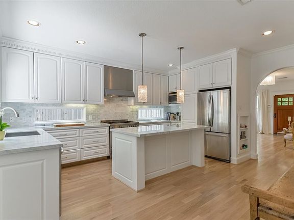 The kitchen has SS appliances, carerra marble countertops, gas cook-top, whimsical pendants over the island, sitting area and detail wood trim and plenty of storage.