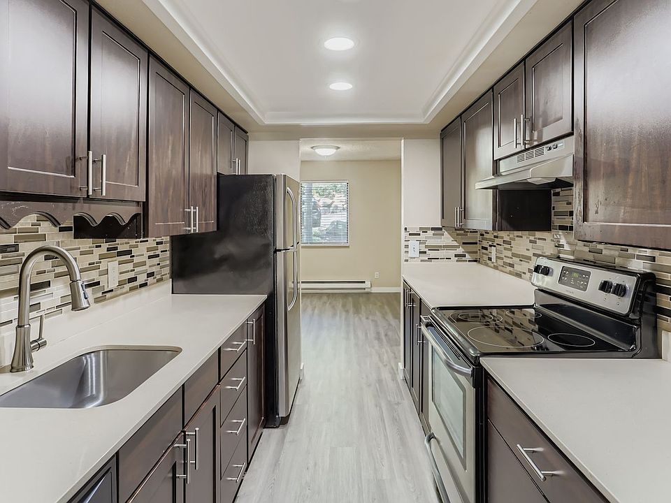 Kitchen with quartz countertops, wood cabinets, stainless steel appliances, and new LVP flooring.