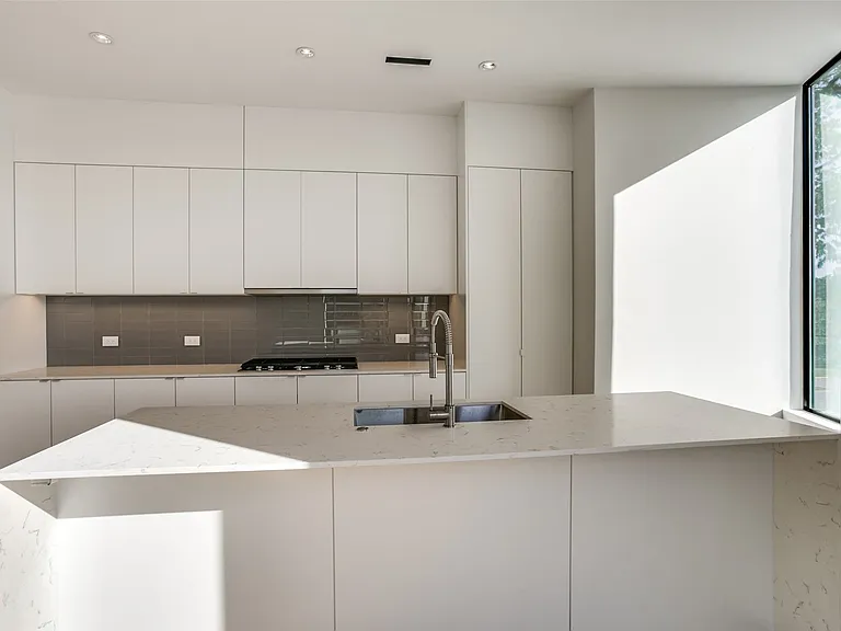 Modern kitchen featuring an expansive island with an undermount sink and gooseneck faucet