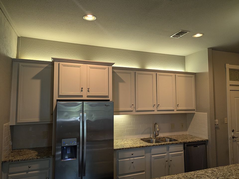 Kitchen with refrigerator, dishwasher, stove/oven, and microwave. Cabinets have pull out drawers. Large countertop has overhang for stools.