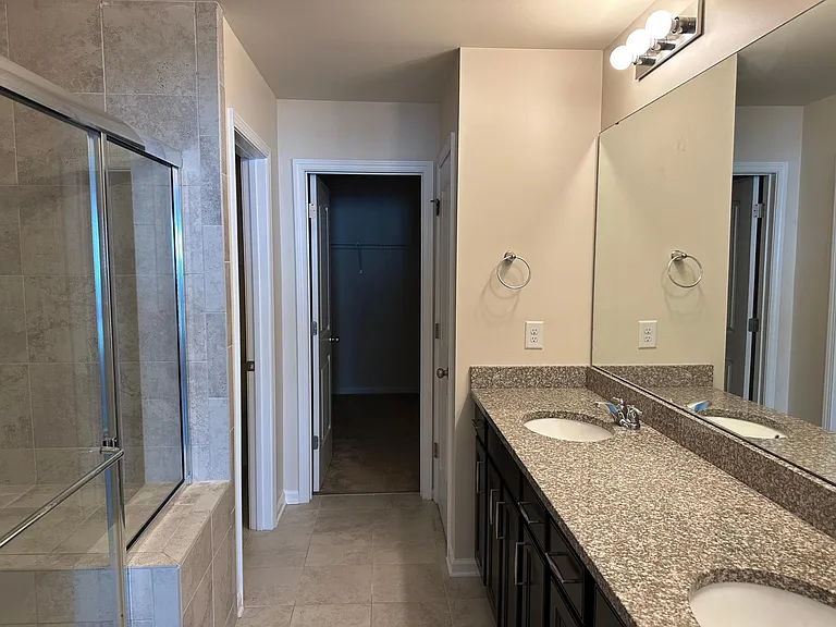 A view into the main bathroom, where you can see the door to the left is the toilet, the door in the center is the walk in closet, and the door to the right is a smaller closet.