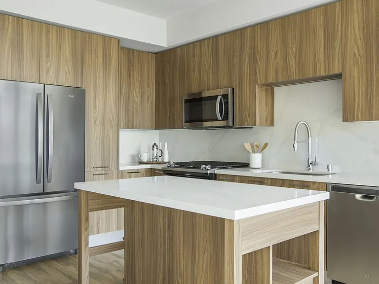 Interior kitchen with warm brown cabinetry, stainless steel appliances, and beautiful backsplash