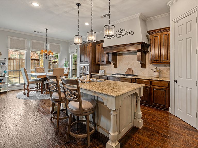 Gourmet kitchen with an oversized granite island, gas cooktop, and custom vent hood