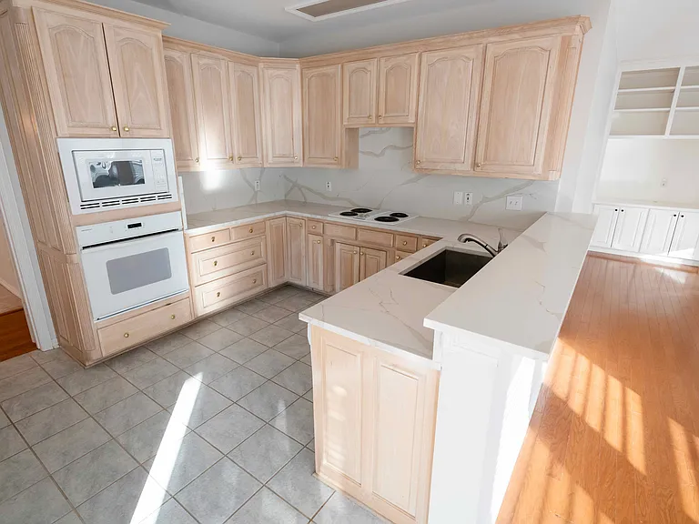 All white kitchen with granite countertops and electric cooktops