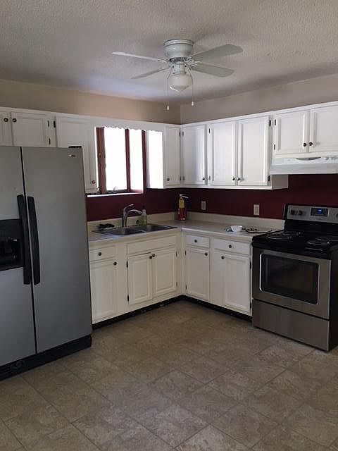 View of kitchen from living room. Stainless steel fridge was replaced with a black one.