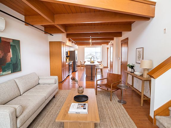 Spacious open layout at Union Bay Lofts with vaulted wood-beam ceilings connecting the living room to the kitchen.